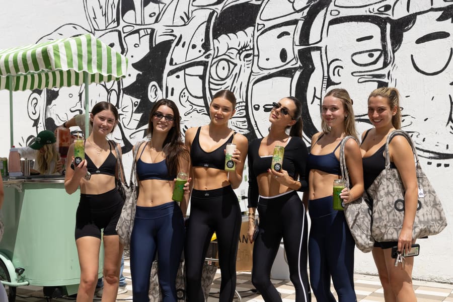Friends holding Matcha Bike cans in front of the mural wall